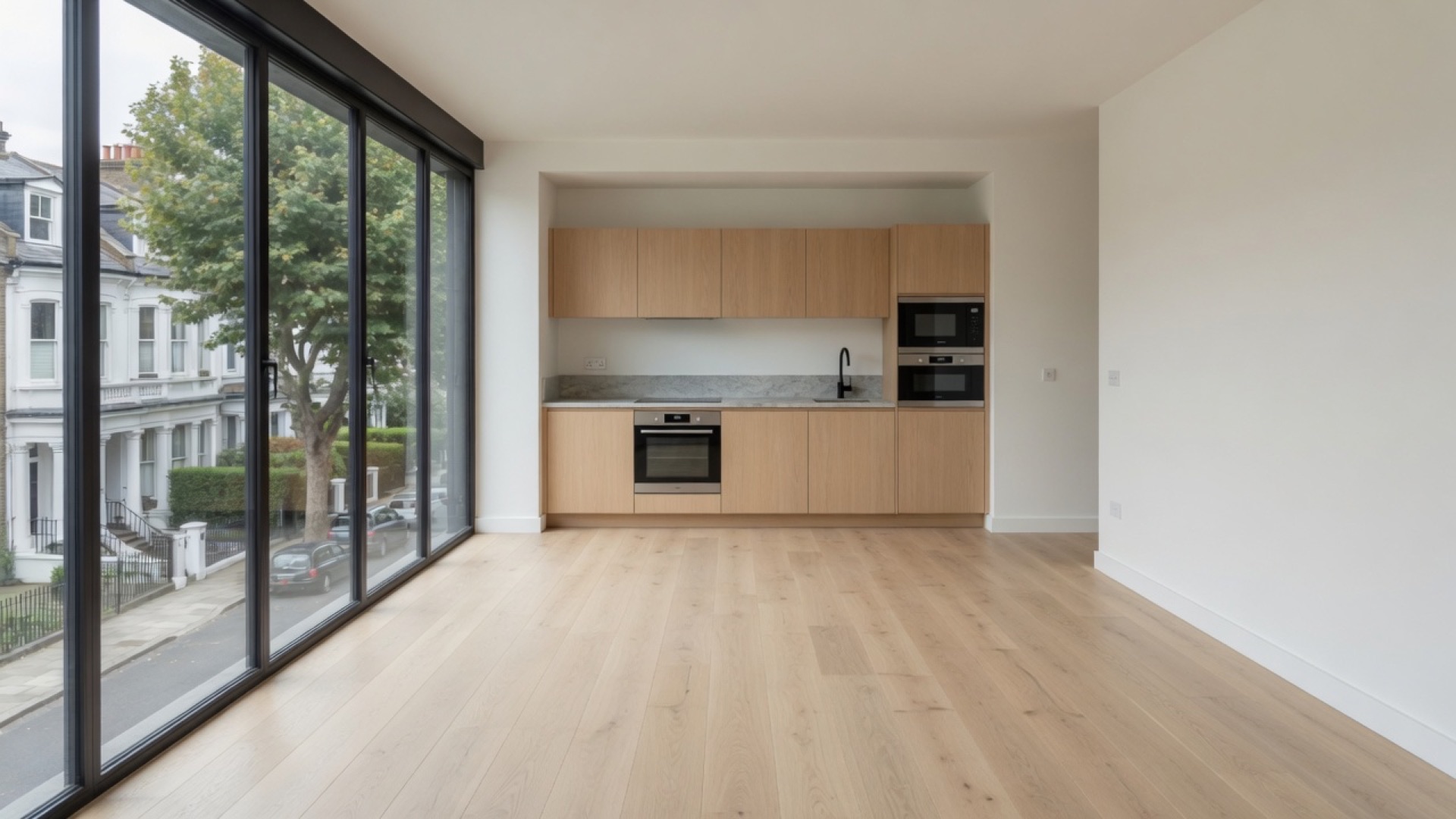 The same room after plaster and an oak floor, with a fitted oak kitchen in the far alcove.